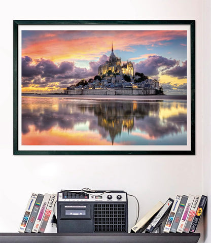 Framed picture of Mont Saint-Michel at sunset, reflected in water. Below it, a boombox and VHS tapes