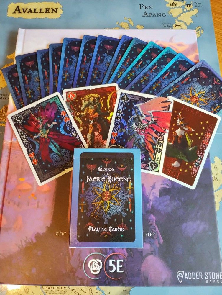 Against the Faerie Queene playing cards (fanned and boxed) on a D&D 5E fantasy book and map