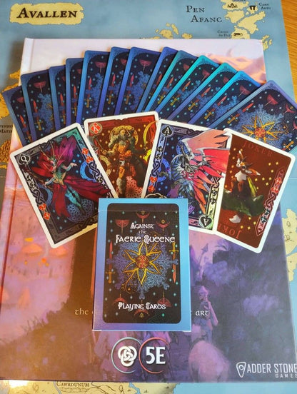 Against the Faerie Queene playing cards (fanned and boxed) on a D&D 5E fantasy book and map