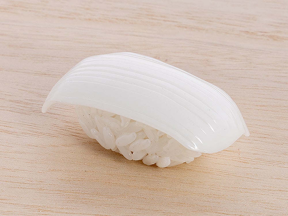 A piece of translucent white squid nigiri sushi rests on a light wooden surface