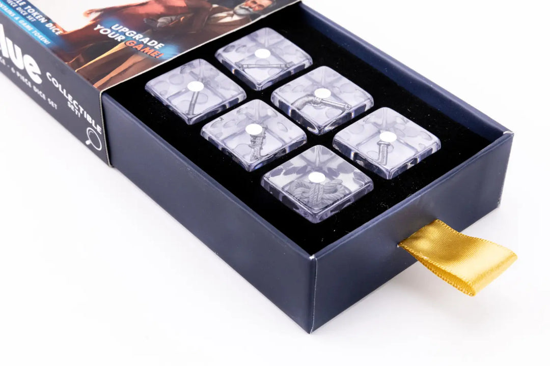Open blue box holds six clear dice, each embedding a Clue game weapon like a wrench or revolver