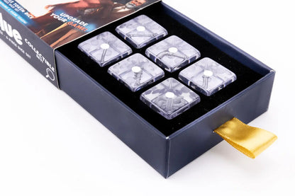 Open blue box holds six clear dice, each embedding a Clue game weapon like a wrench or revolver