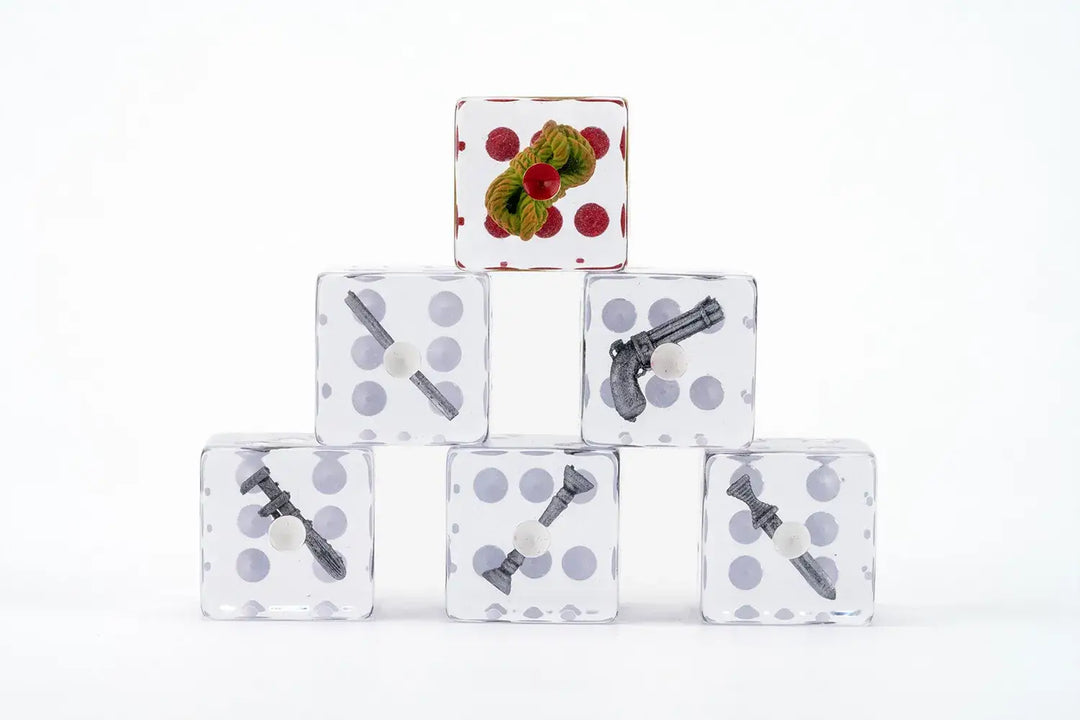 Clear dice stacked in a pyramid. Top die shows green foliage with red dots; others contain miniature Clue game weapons