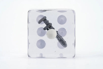 A clear dice contains a small grey caliper measuring a white sphere inside
