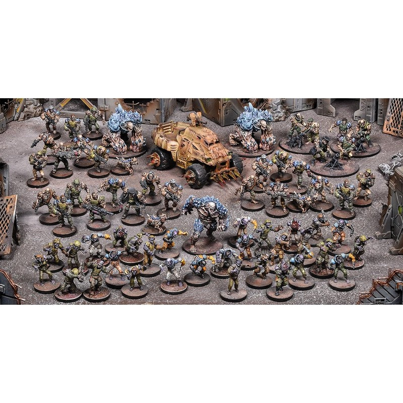 Dozens of painted tabletop wargaming miniatures: soldiers, large blue monsters and a tank on a detailed battlefield diorama