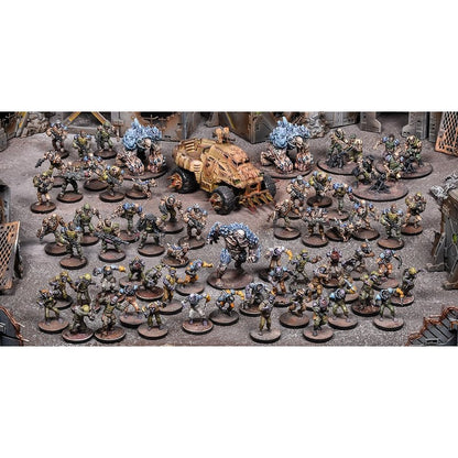 Dozens of painted tabletop wargaming miniatures: soldiers, large blue monsters and a tank on a detailed battlefield diorama