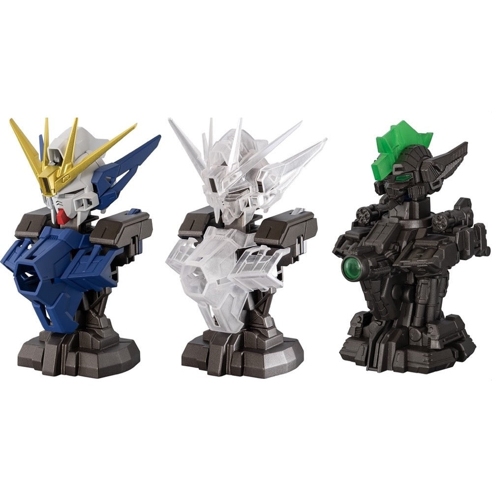 Three Gundam-style robot busts: one blue/gold, one clear plastic, and one dark grey with a green crest