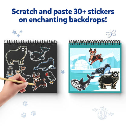 Hand scratches arctic animal stickers from a black pad and pastes them onto an iceberg scene