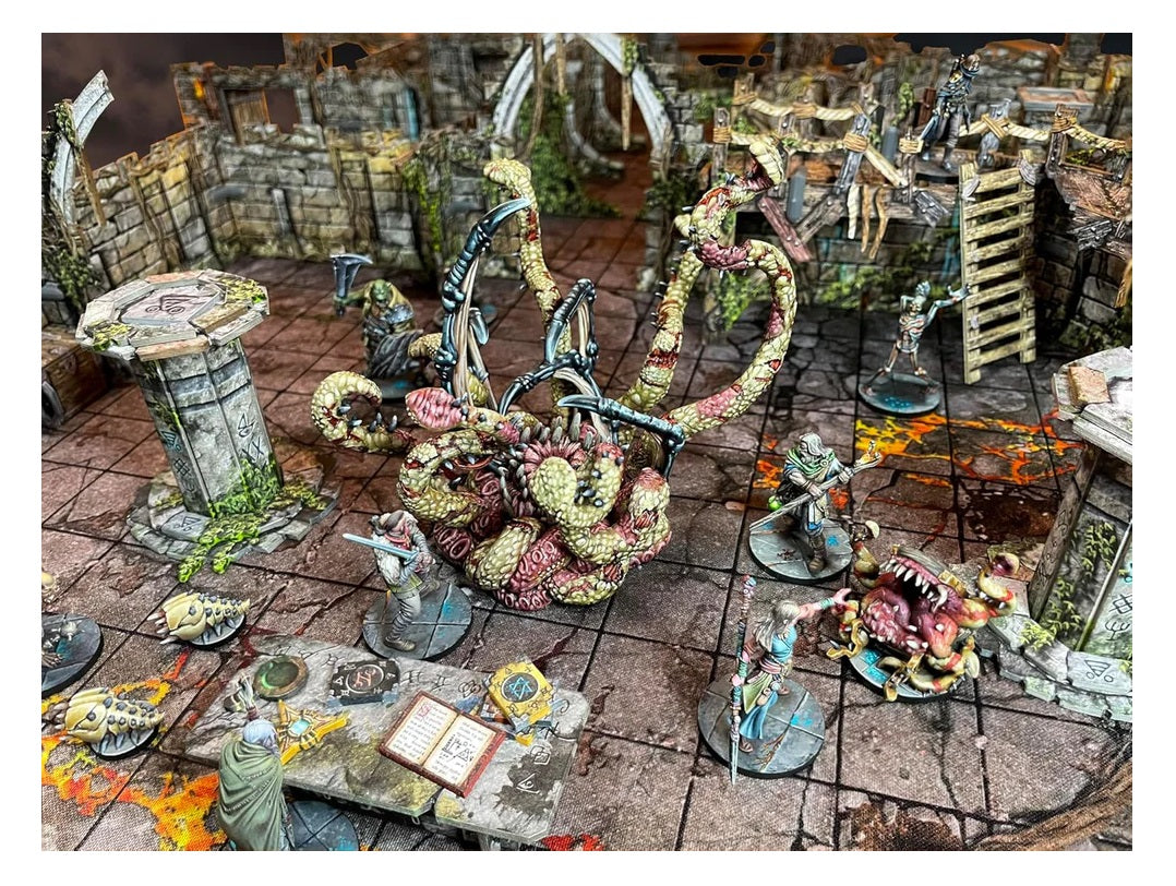 A huge, multi-tentacled monster miniature in a ruined dungeon battles fantasy heroes and creatures on a grid map.