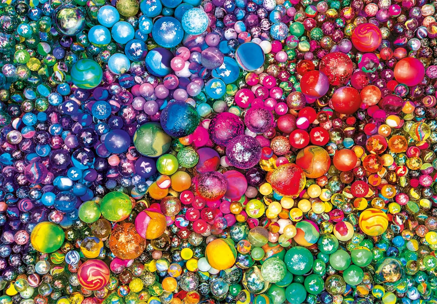 A close-up of hundreds of colorful marbles of various sizes, arranged in a vibrant rainbow gradient