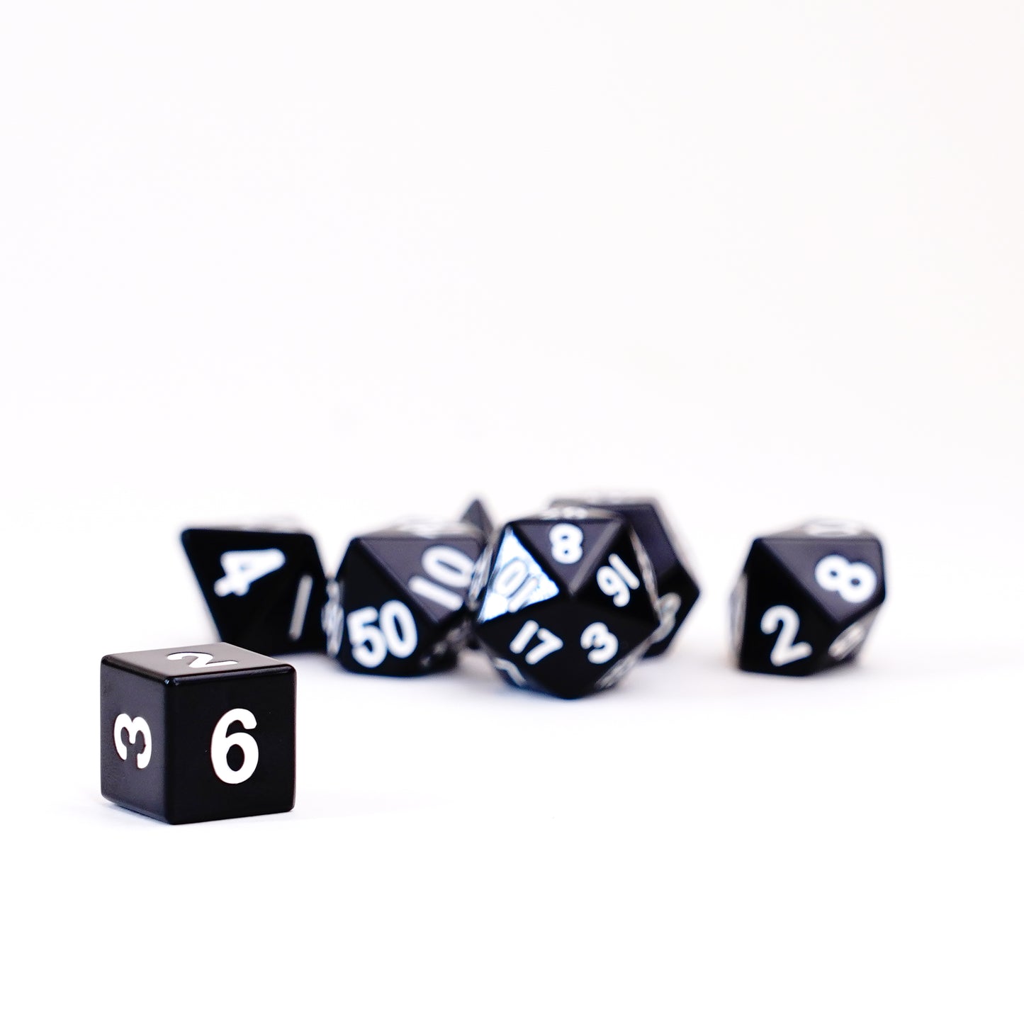 Angled view of black metal polyhedral dice set with silver numbering high-quality tabletop gaming dice