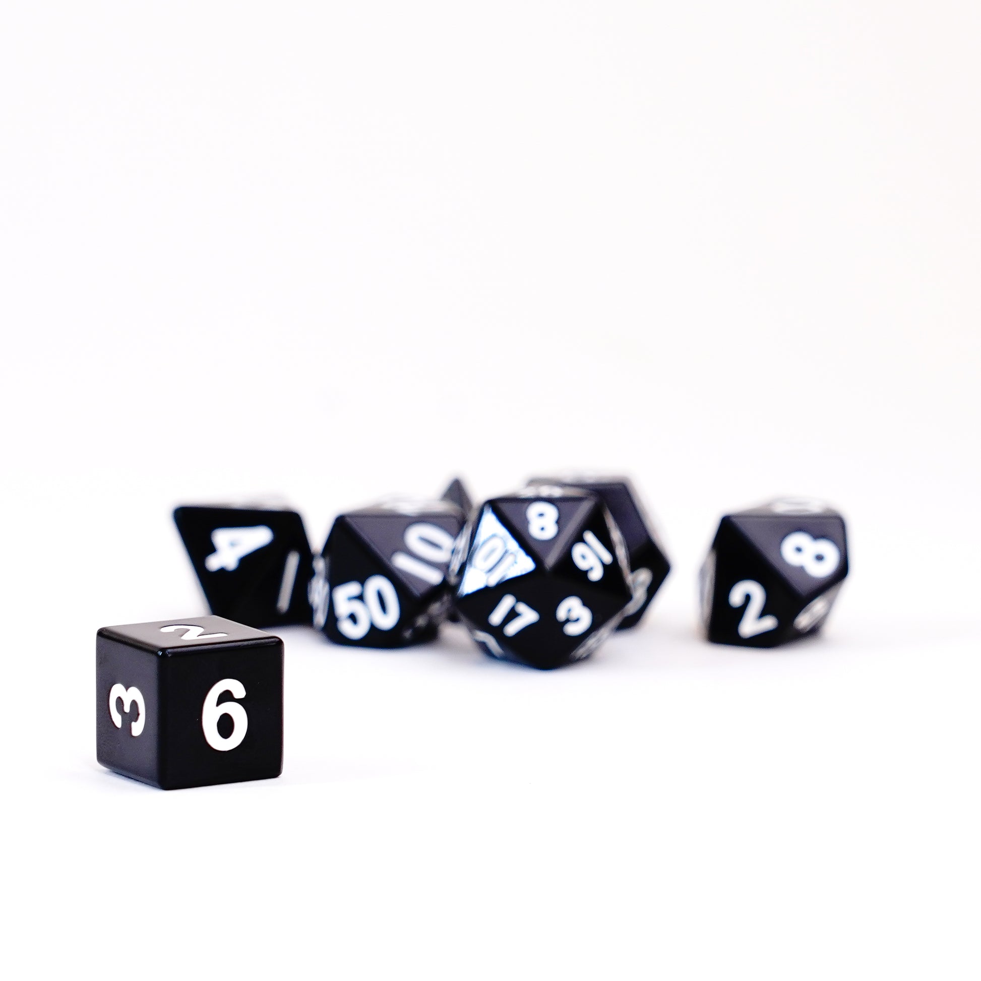 Angled view of black metal polyhedral dice set with silver numbering high-quality tabletop gaming dice