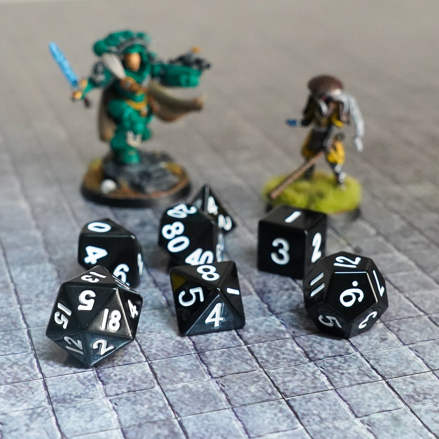 Black metal dice set with silver numbers displayed in a scattered layout on a black surface