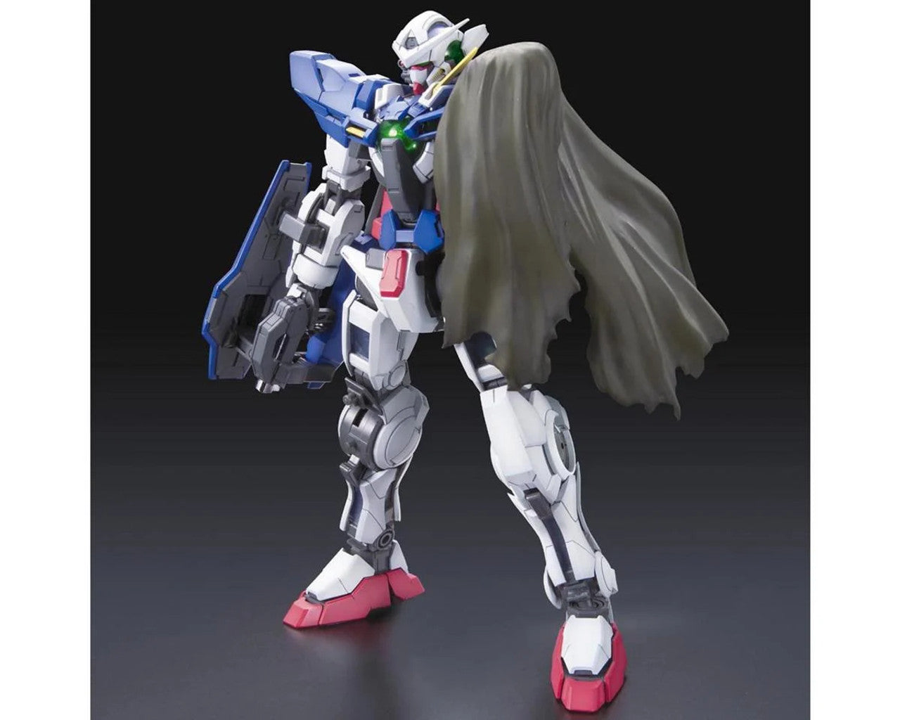 A white, blue, and red Gundam Exia model stands against a dark background, wearing a flowing grey cape and shield