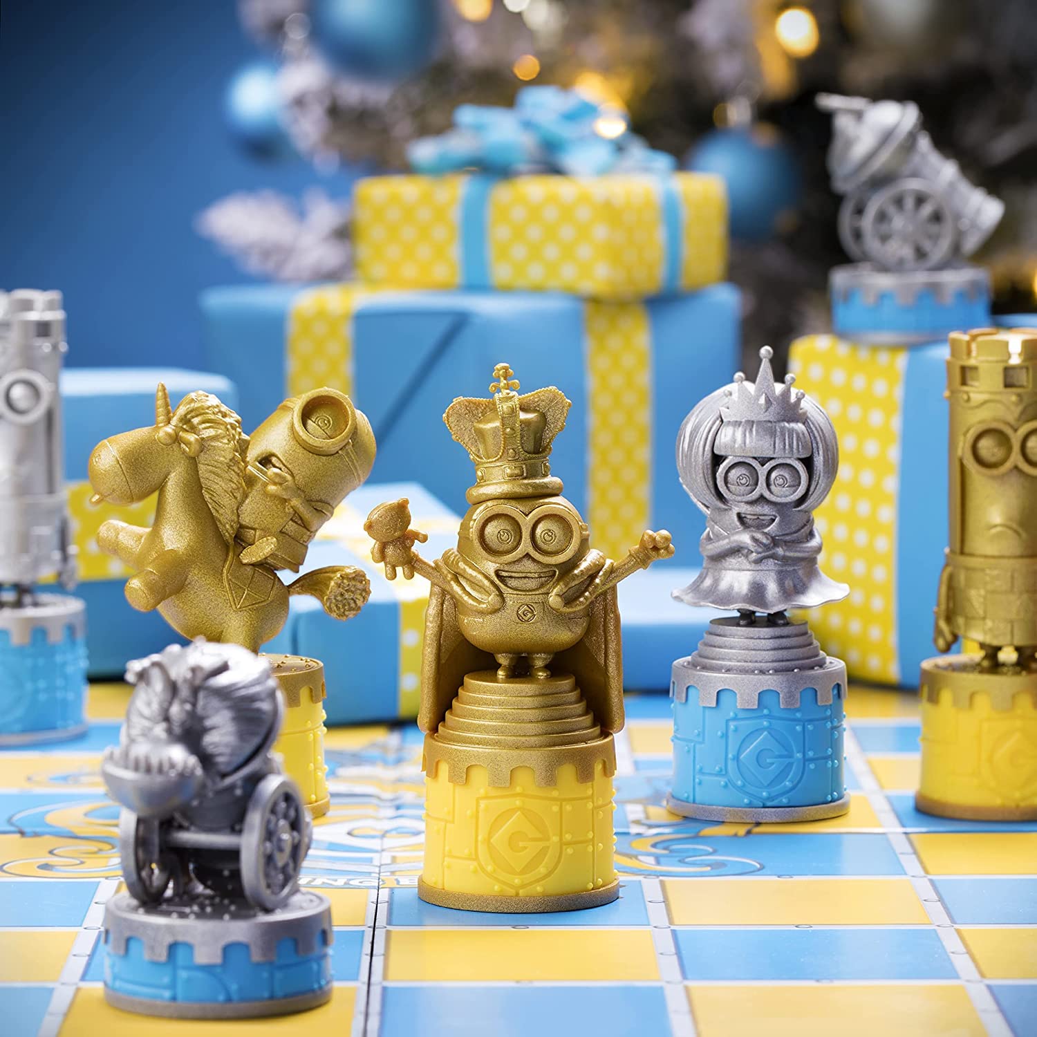 Gold and silver Minion chess pieces on a blue and yellow board, with blurred Christmas gifts in the background