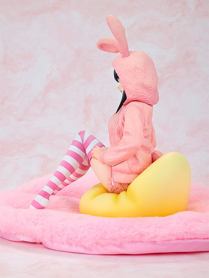 Anime figure in pink bunny onesie and striped socks, sitting on a yellow heart cushion on a pink fluffy surface