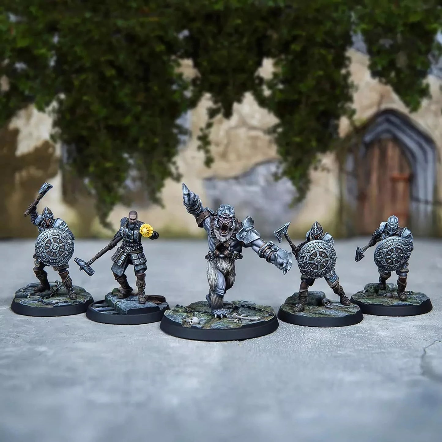 Five painted fantasy miniatures: an armored bear-creature charges, flanked by four warriors with shields & axes.