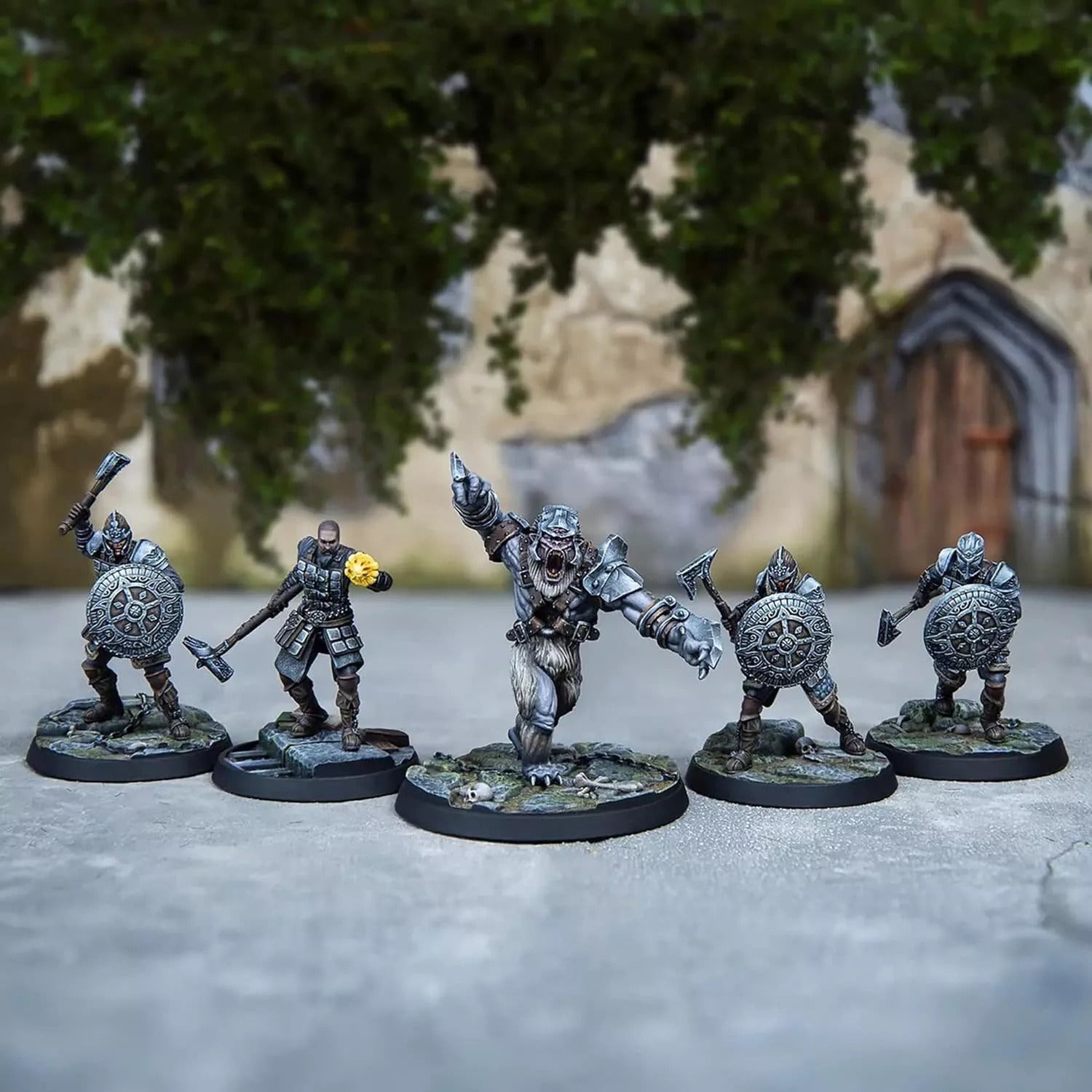 Five painted fantasy miniatures: an armored bear-creature charges, flanked by four warriors with shields & axes.