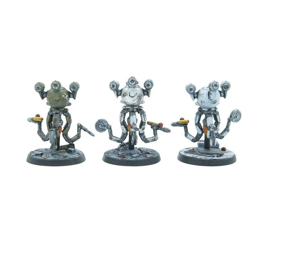 Three weathered, multi-eyed robot miniatures (green, white, light blue), each holding a hotdog on a serving tray.