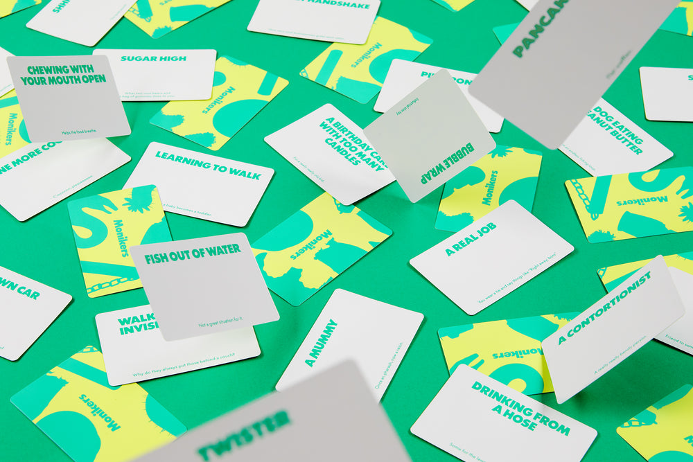 Scattered Monikers game cards (white, teal, and yellow) on a vibrant green background