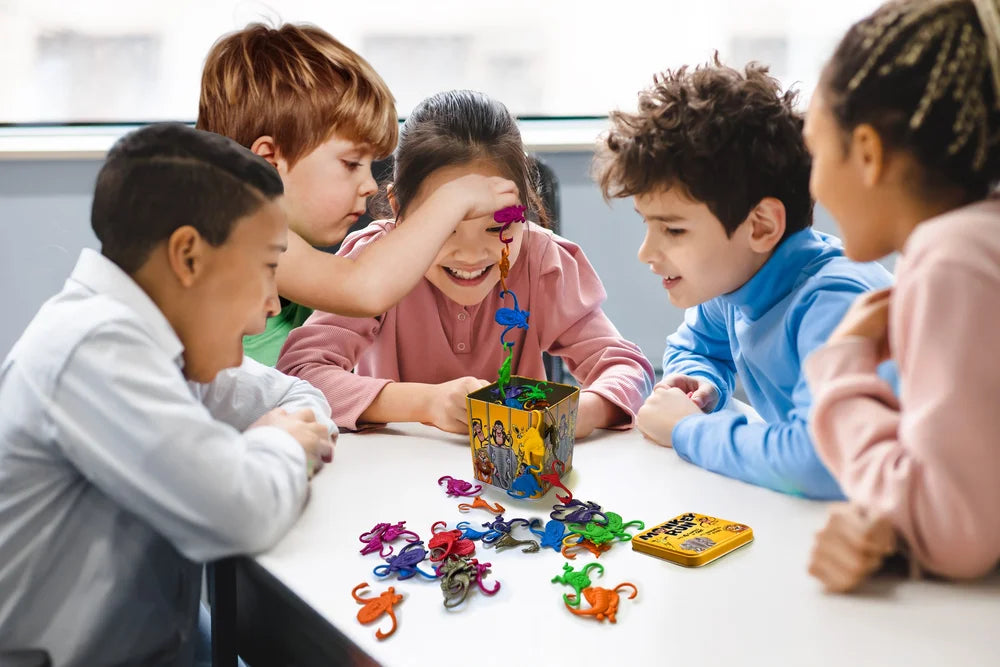 Five diverse children intently play a &#39;Monkey Run&#39; game, with a smiling girl adding a colorful monkey to a chain