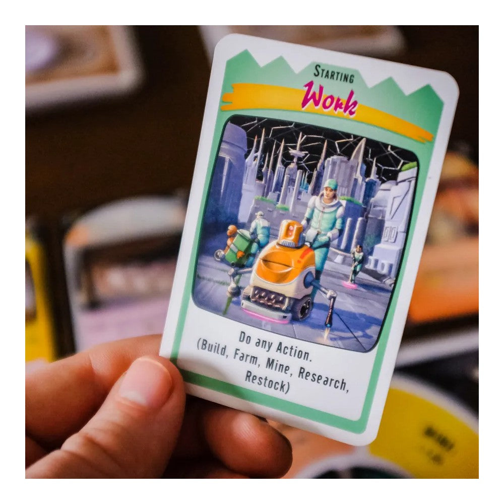 Hand holds "Starting Work" game card, illustrating a futuristic worker guiding an orange robot in a sci-fi city