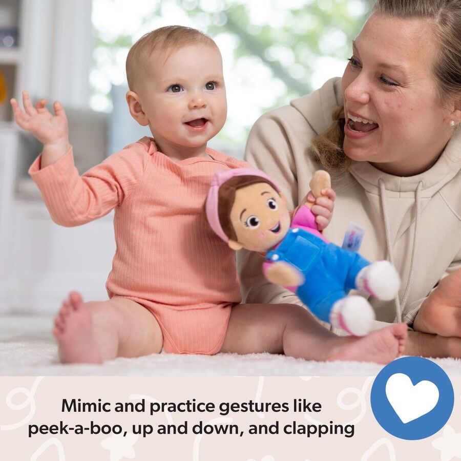 Smiling baby raises an arm, playing with a happy adult holding a plush doll