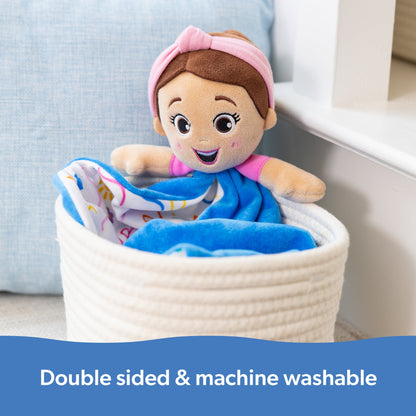 Smiling plush doll with pink headband and top, sits in a white woven basket with a blue blanket, features: double sided & machine washable