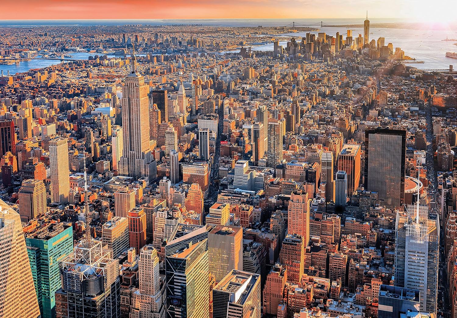 Aerial panorama of New York City at golden hour with the Empire State Building and countless skyscrapers.