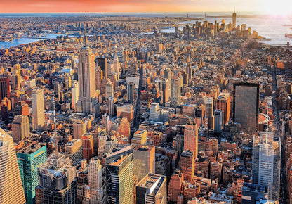 Aerial panorama of New York City at golden hour with the Empire State Building and countless skyscrapers.