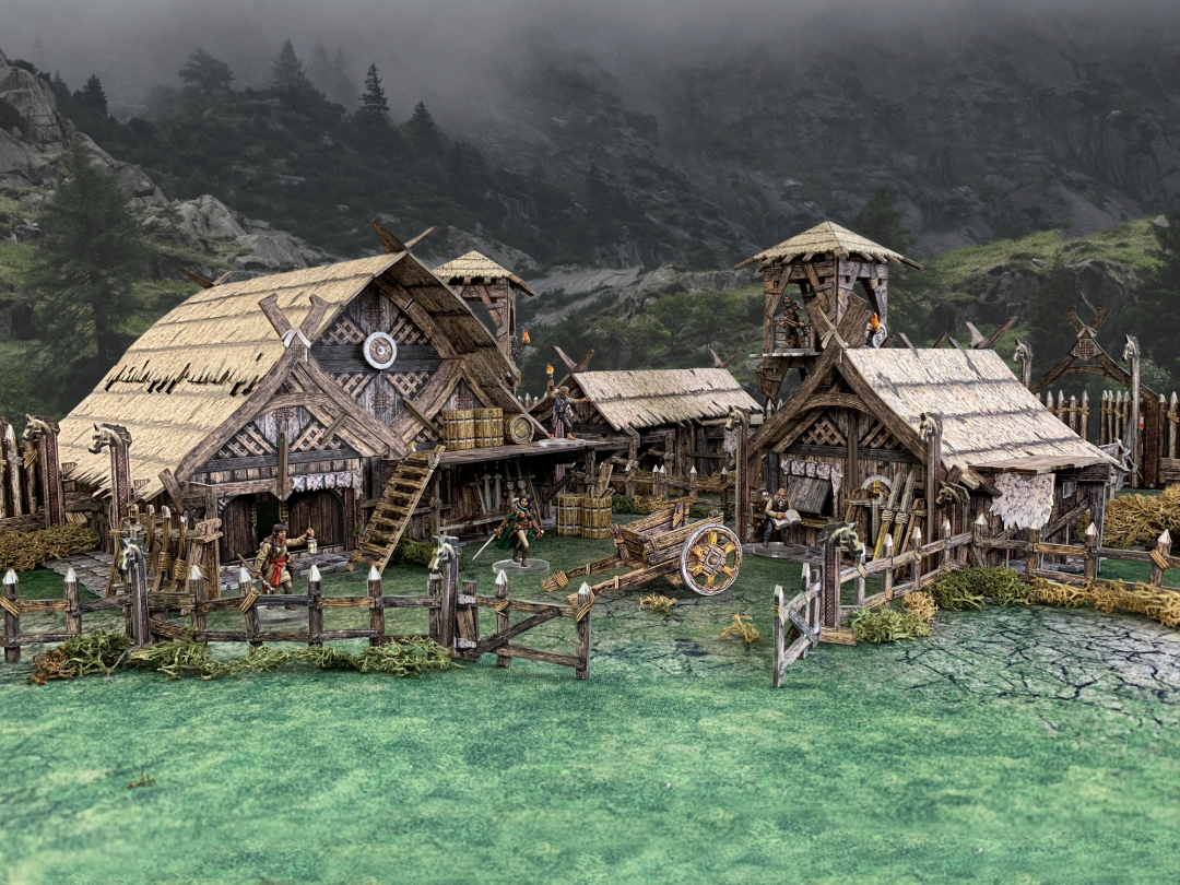 Detailed diorama of a Viking settlement: thatched wooden buildings, figures, a cart, a watchtower, and misty mountains.