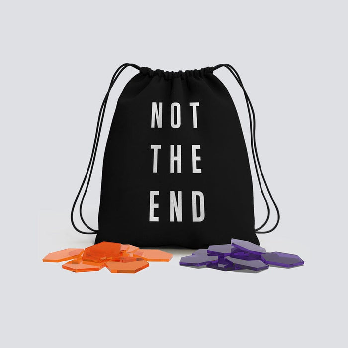 A black drawstring bag printed with NOT THE END, with piles of orange and purple hexagonal tokens in front