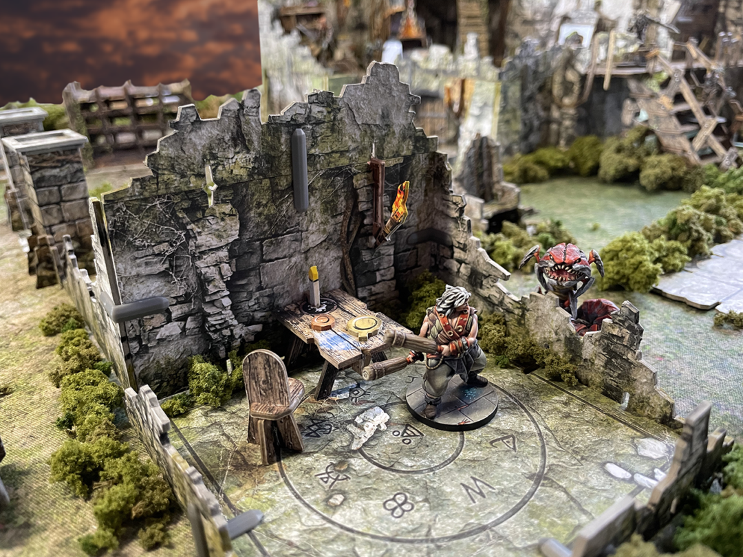 Battle Systems Crypts and Caverns Dungeon Upgrade Pack showing stone ruins a table with candle and a monster miniature near a hero figure for tabletop gaming