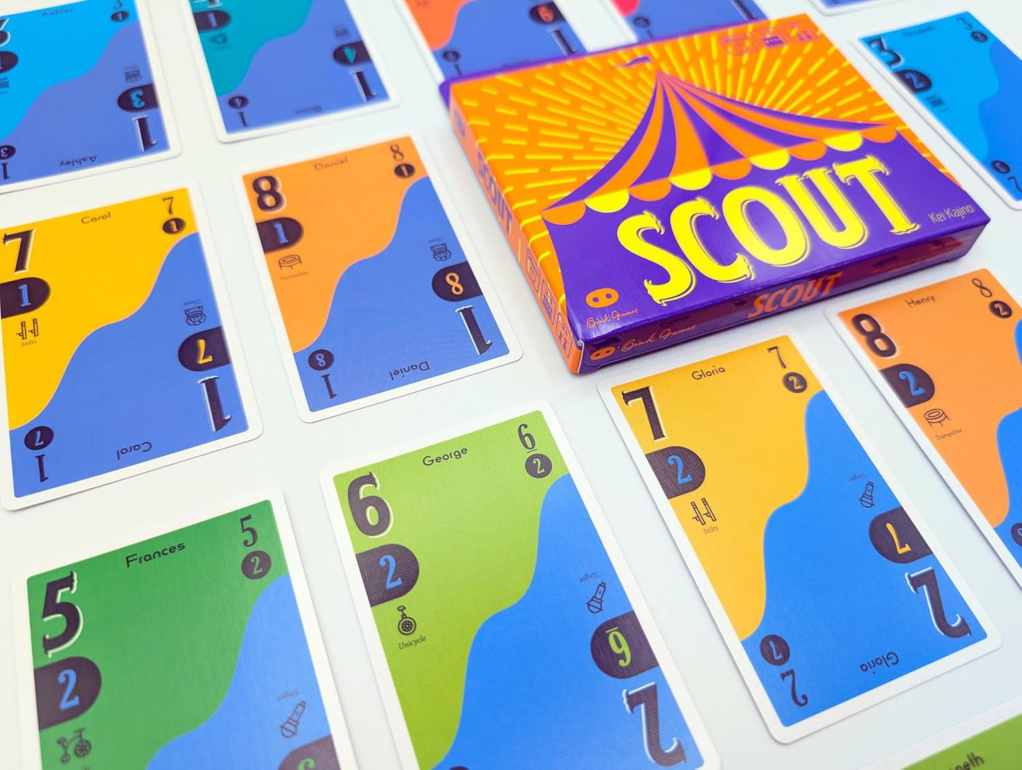 Colorful Scout game cards with numbers and icons surround the circus tent box on a white surface