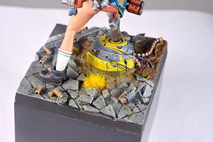 Miniature figure's leg -  weapon -  and a glowing yellow orb on a battle-damaged base with rubble and bullet casings