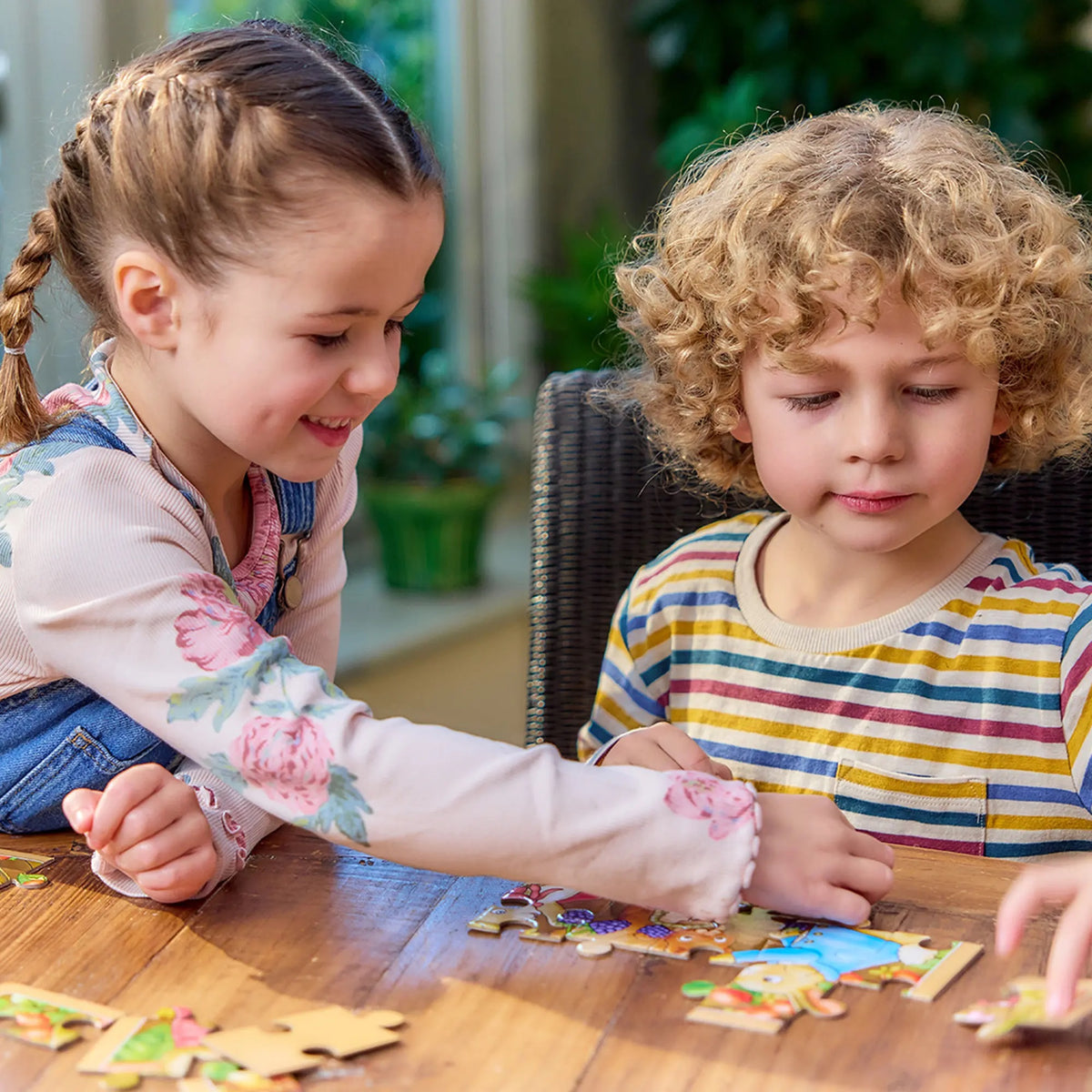 Smiling girl and boy assembling a colorful puzzle on a wooden table