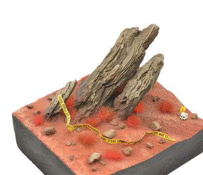 A miniature diorama showcases bright red AK Interactive 4mm wargame tufts scattered across red earth with large rocks, yellow crime scene tape, and a tiny skull
