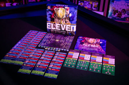 Eleven International Cup board game expansion with rulebook score cards and player pieces on a dark table