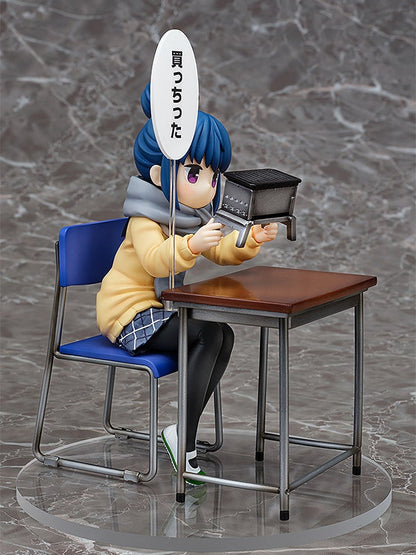 Anime figure of a girl sitting at a school desk holding a miniature barbecue grill with a speech bubble saying I bought it