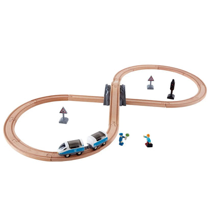 Blue toy train on a wooden figure-eight track with a tunnel, signs, and two small conductor and passenger figures