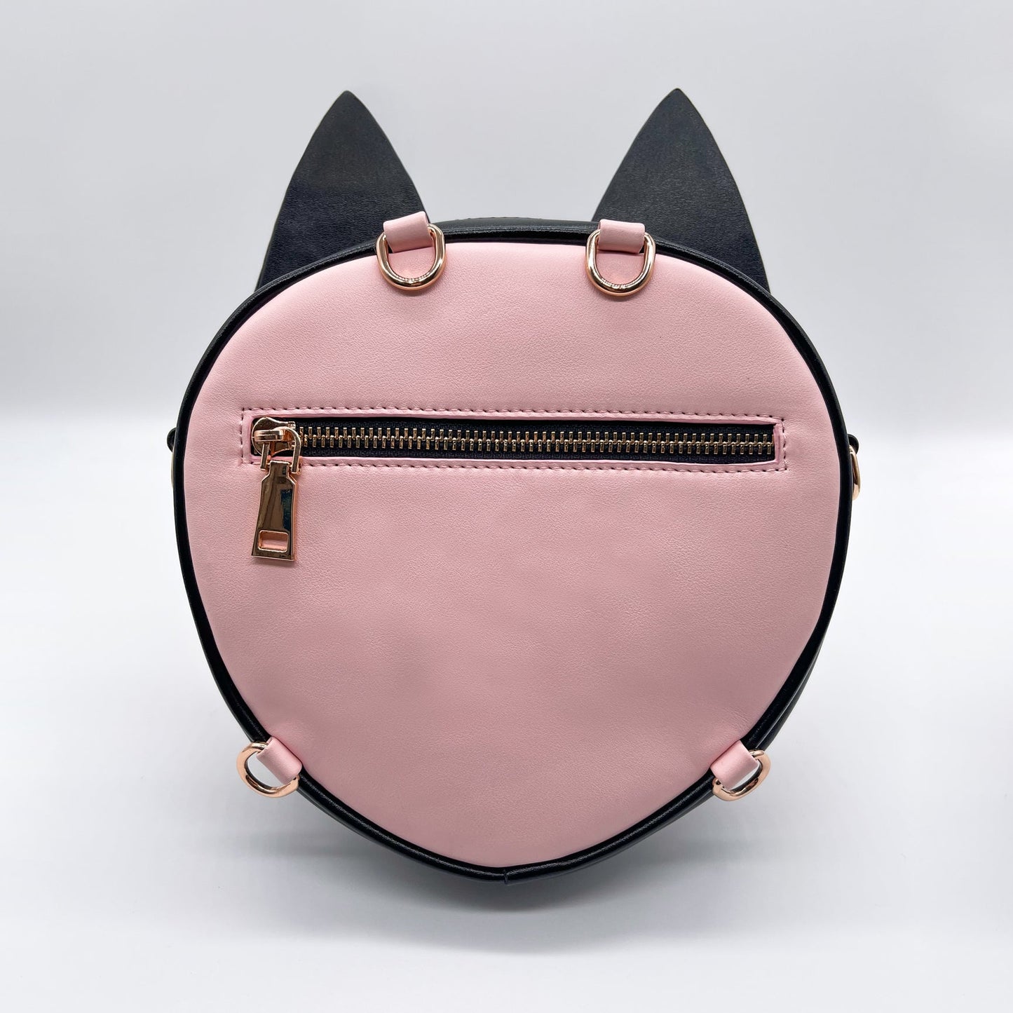 Pink and black round cat-shaped purse with gold zipper and D-rings, on a white background.