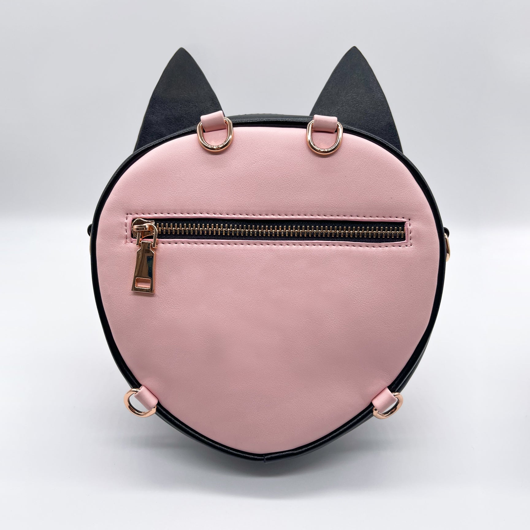 Pink and black round cat-shaped purse with gold zipper and D-rings, on a white background.