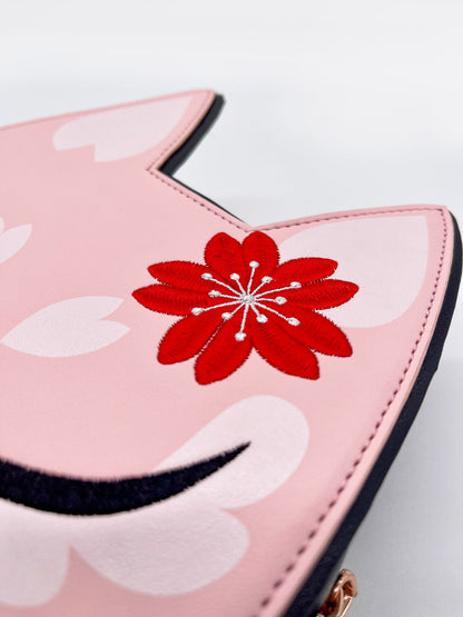 Pink cat-eared wallet with a prominent red embroidered cherry blossom, white petals, and black trim.