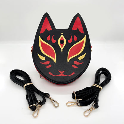 Black, red, and gold Kitsune mask-inspired purse, shown with two coiled black straps.