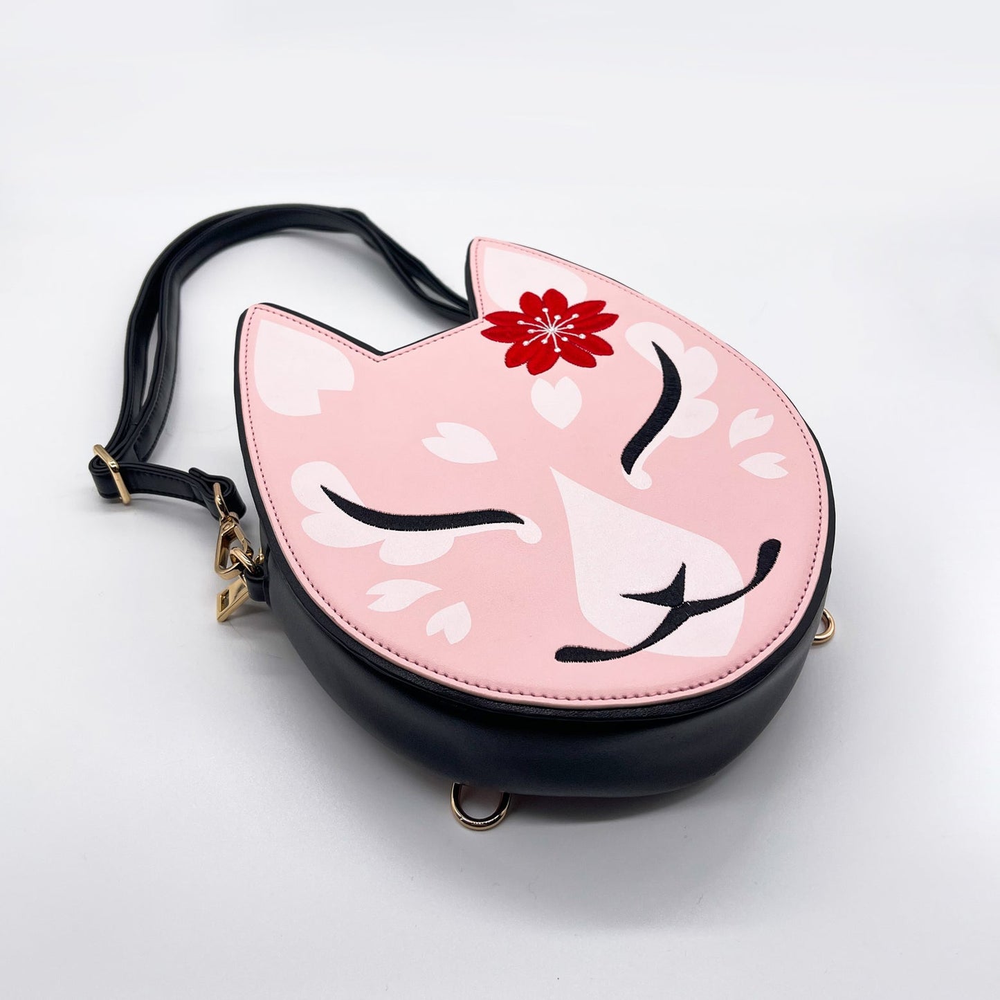 Pink cat purse with a red flower, white sakura petals, and a black strap.