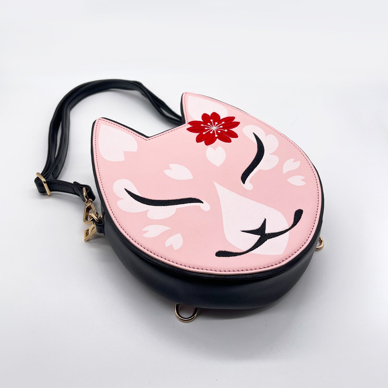 Pink cat purse with a red flower, white sakura petals, and a black strap.