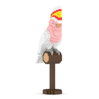 Block-style pink and white cockatoo with a yellow and red crest, perched on a brown stand
