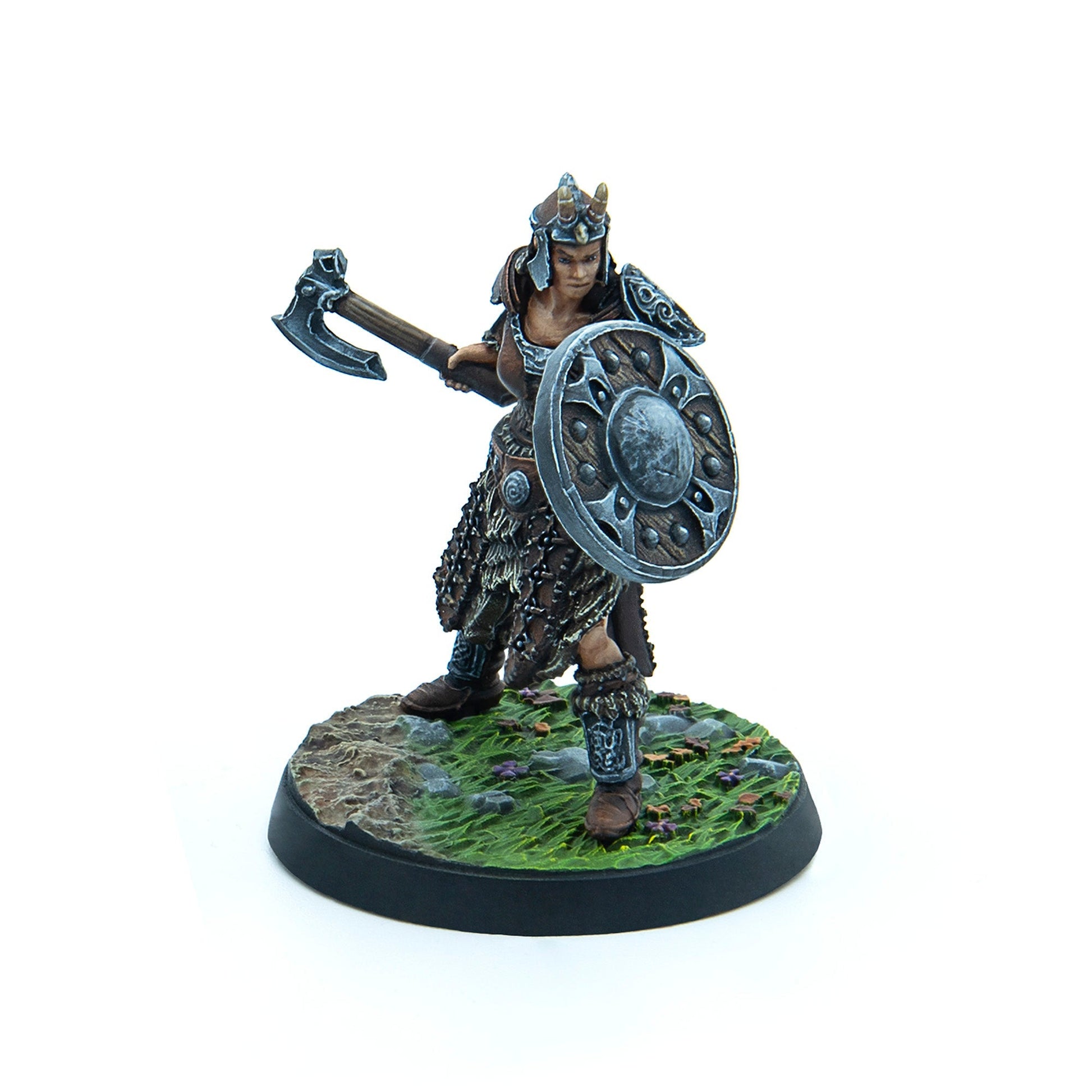 Miniature female warrior in fur armor and horned helmet, holding a raised axe and shield, on a grassy base