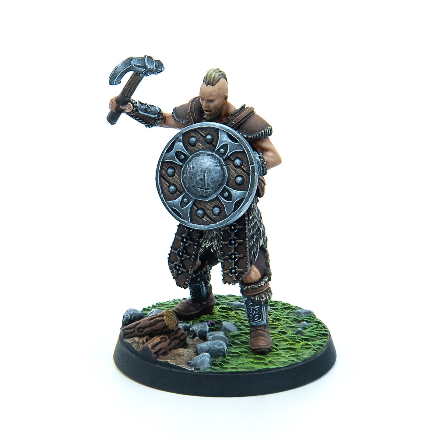 A roaring, mohawked barbarian warrior miniature raises a hammer and holds a shield, standing on a grassy base