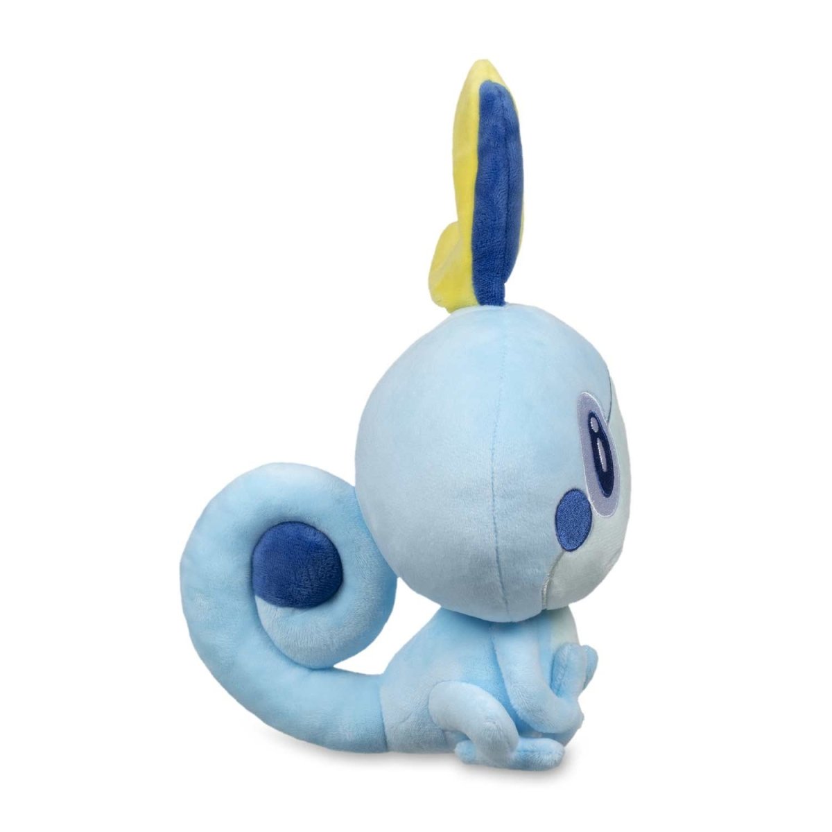 Light blue Sobble plush toy sitting, facing right, with a yellow head fin and curled tail